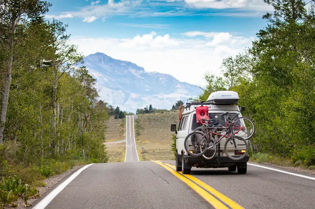 Camping-car : bien choisir son assurance avant le départ 2 Courtier Assurances et Financements Rennes Camping-car aménagé traversant un paysage de montagne européen avec des vélos à l'arrière