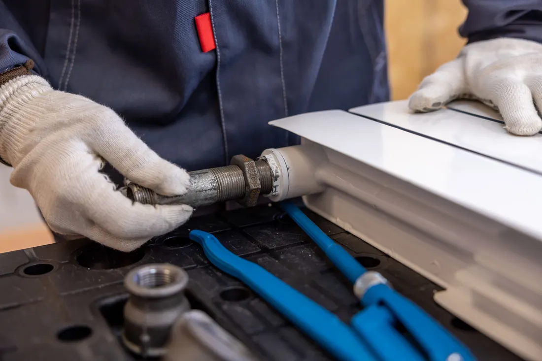 Assurance RC Pro plombier chauffagiste : prix, garanties et obligation 2026 1 Courtier Assurances et Financements Rennes Plombier chauffagiste posant un radiateur, garanties RC Pro
