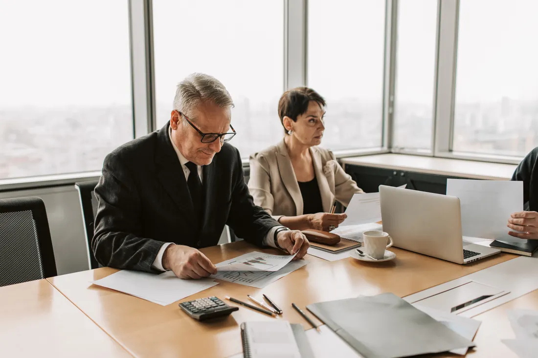 Responsabilité des dirigeants : à quoi sert l'assurance RCMS / D&O ? 1 Courtier Assurances et Financements Rennes Dirigeants examinant des documents en reunion lors d'un audit de risque de gouvernance d'entreprise